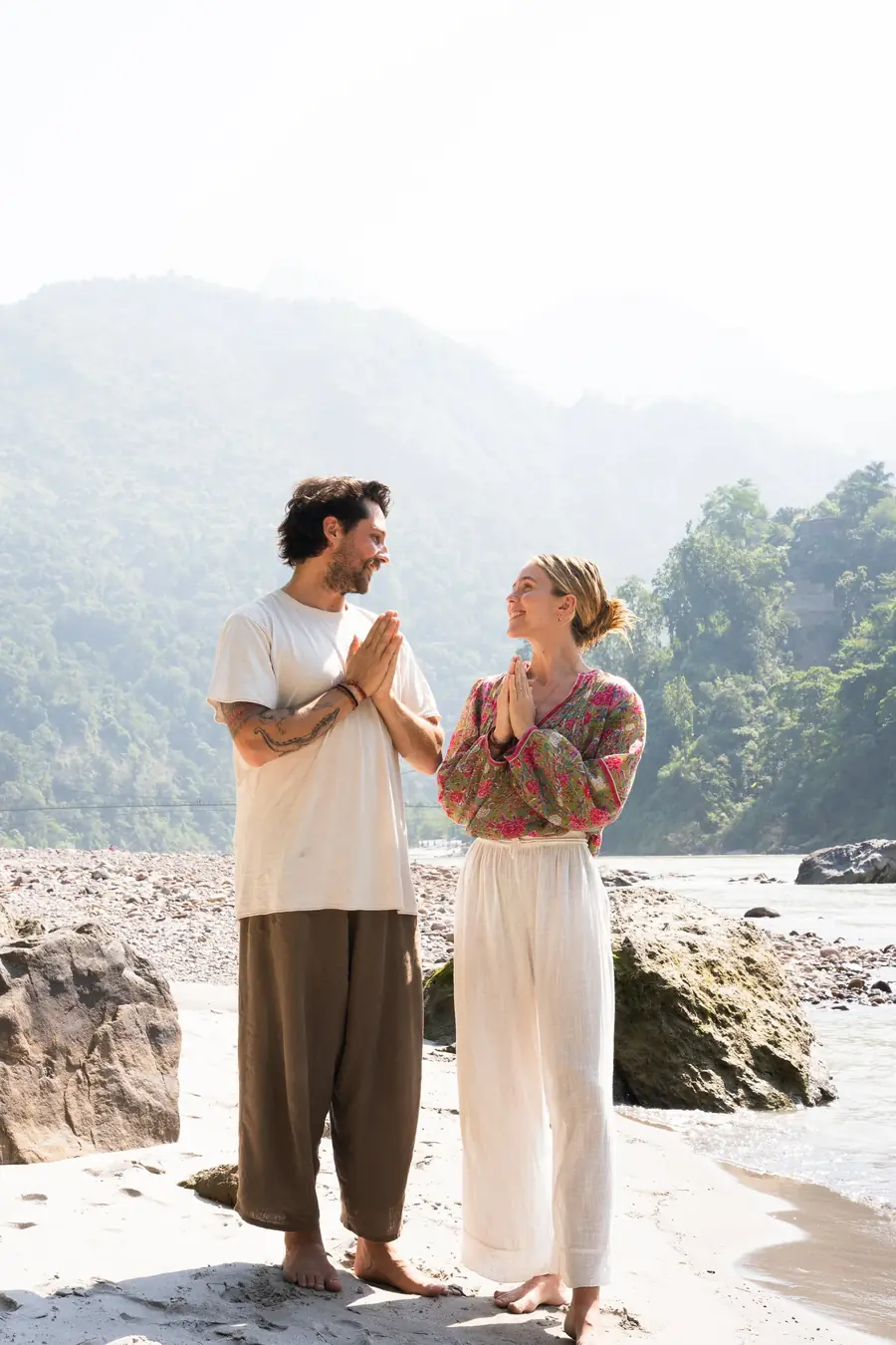 Aaron and Paige with hands in prayer beside the Ganges