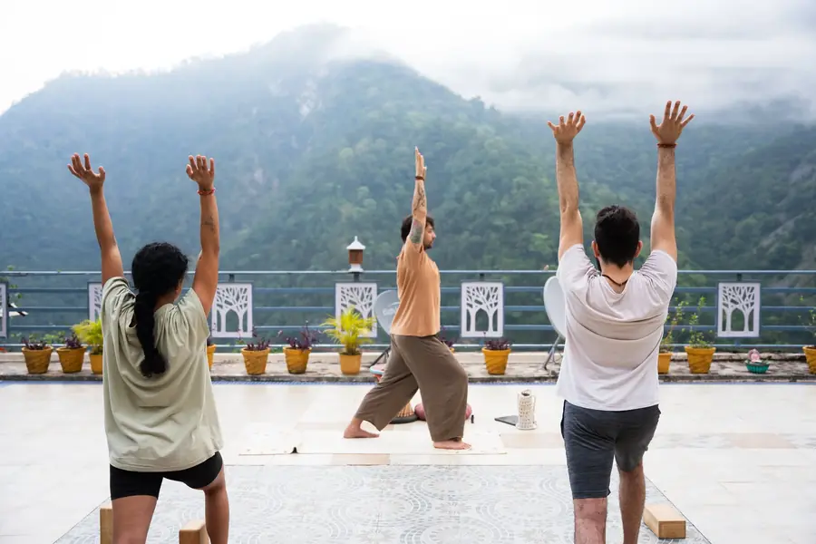 Students practising on a rooftop in Rishikesh with mountains behind