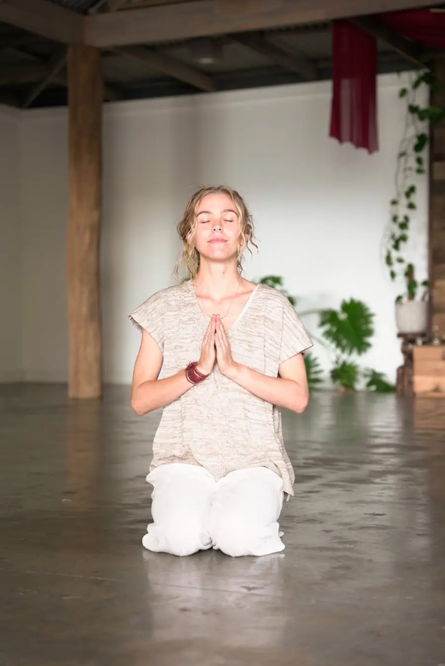 A student kneeling with hands at heart, eyes closed