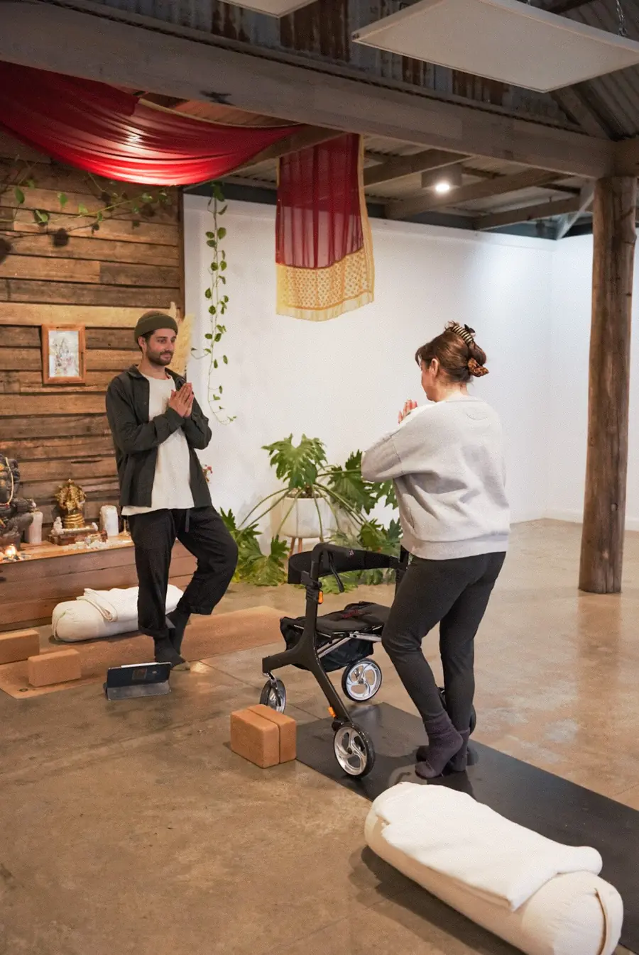 Aaron supporting a client with a walker through a standing practice