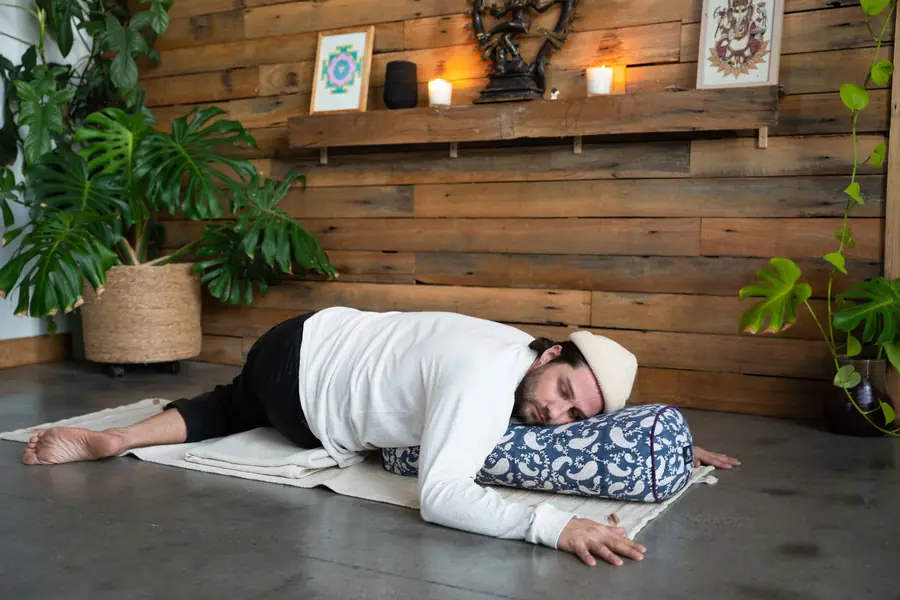 Aaron in a supported Yin pose over a bolster