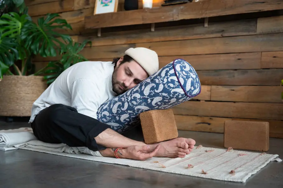 Aaron resting forward over a bolster in a Yin pose